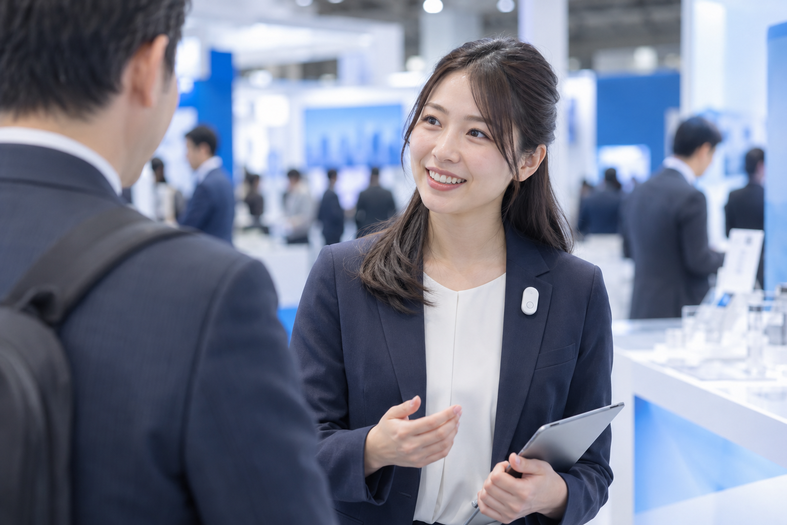 展示会ブースで来場者と会話するスタッフのイメージ